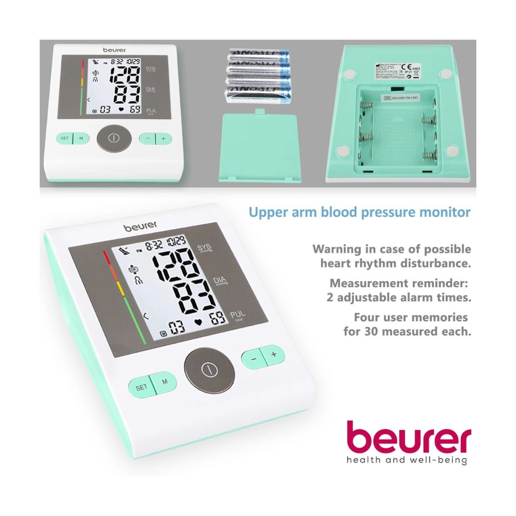 Beurer BM 29 upper arm blood pressure monitor displayed with its open back battery compartment, four AA batteries, and feature highlights for four-user memory and dual alarm reminders.