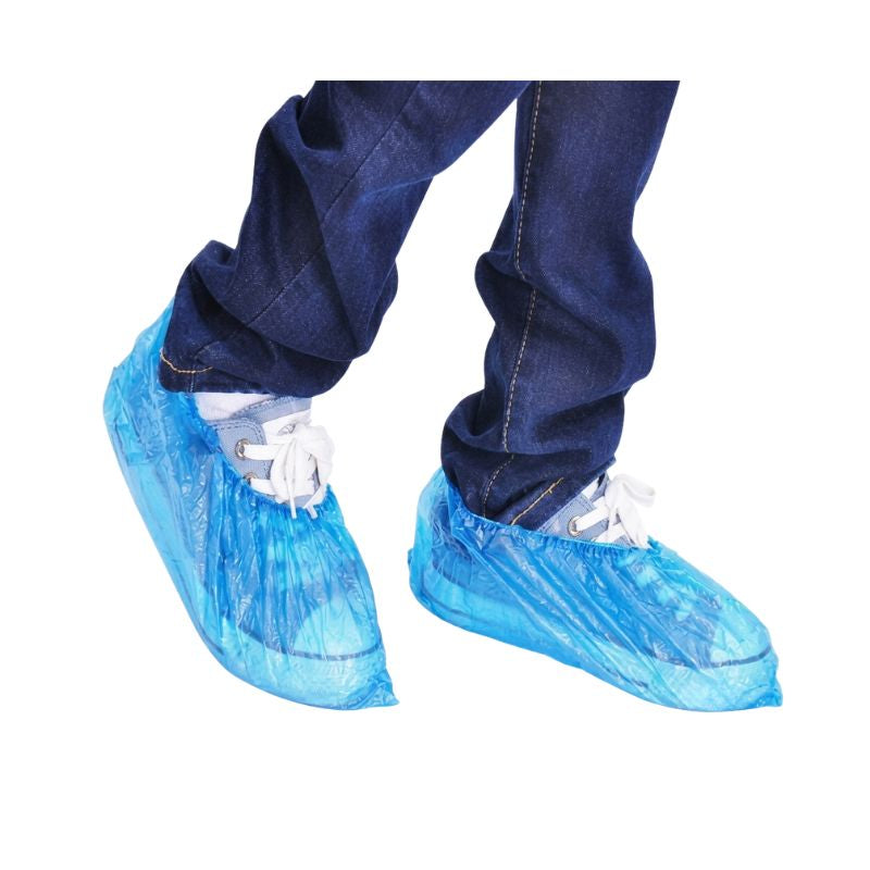 Person wearing blue jeans and casual sneakers fitted with a disposable plastic shoe cover for reliable indoor floor protection.